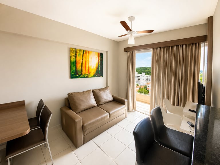 Modern apartment living room with tan leather sofa, glass balcony doors, ceiling fan, and city view